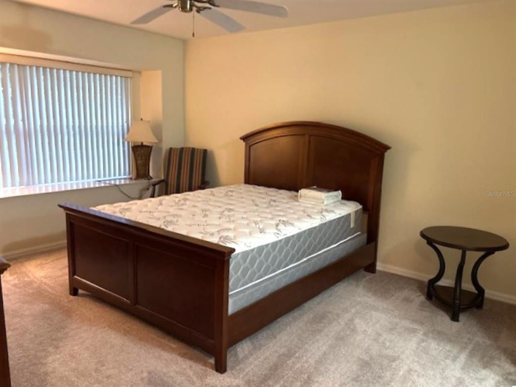 7867 Southwest 115th Loop Ocala, FL 34476 - Photo 29 of 40 a bed sitting in a bedroom next to a window and a chandelier