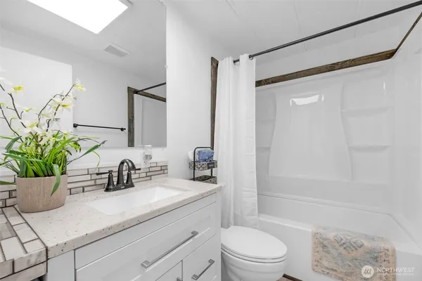 a bathroom with a sink a toilet a mirror a vanity and shower