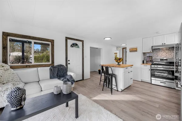 a living room with furniture and a large window with kitchen view