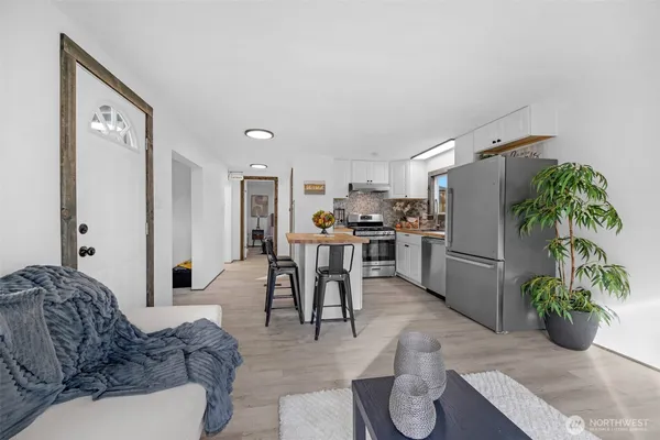 a living room with furniture potted plant and kitchen appliances