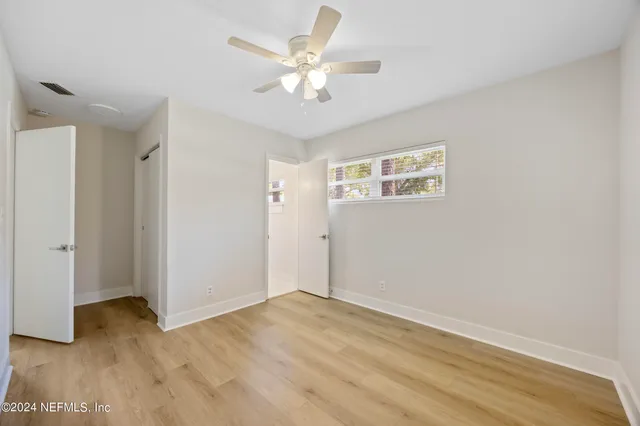 an empty room with wooden floor and ceiling fan