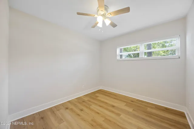 an empty room with a window and a fan