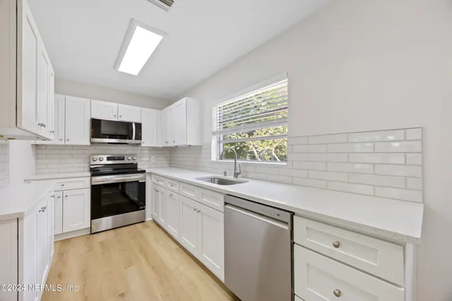 a kitchen with granite countertop white cabinets and white appliances