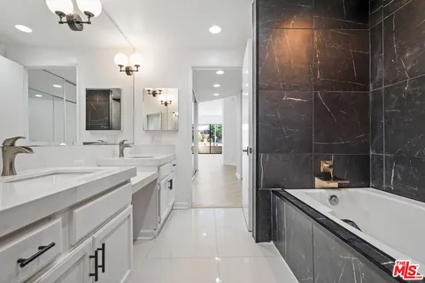 a bathroom with a granite countertop sink mirror and bathtub
