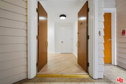 a view of a hallway with wooden floor and a bathroom