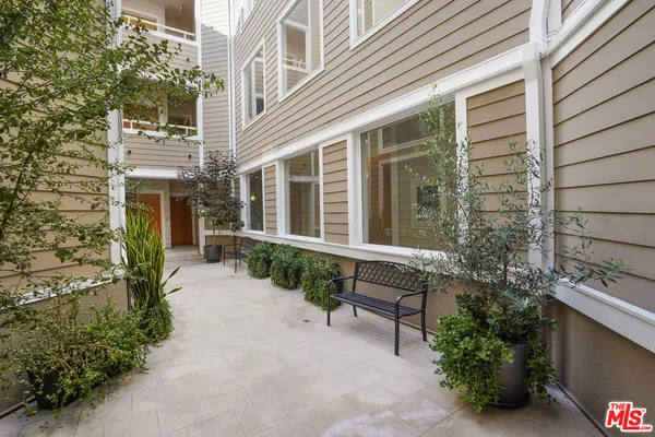 a view of a house with potted plants and a bench