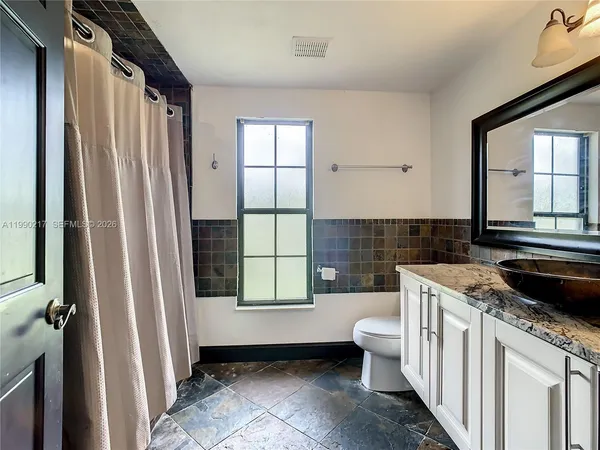 an empty room with wooden floor chandelier fan and windows