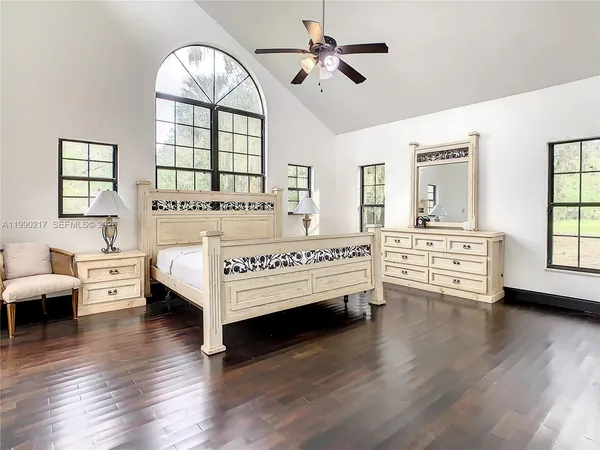 a bedroom with a bed and a large window with wooden floor