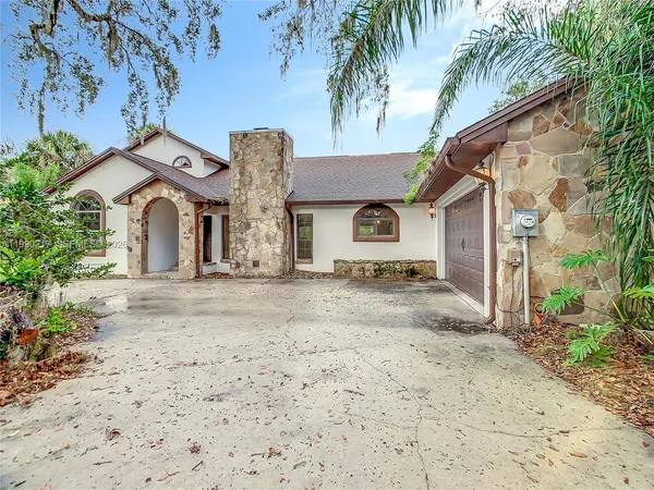 a view of a white house with a large tree and wooden fence