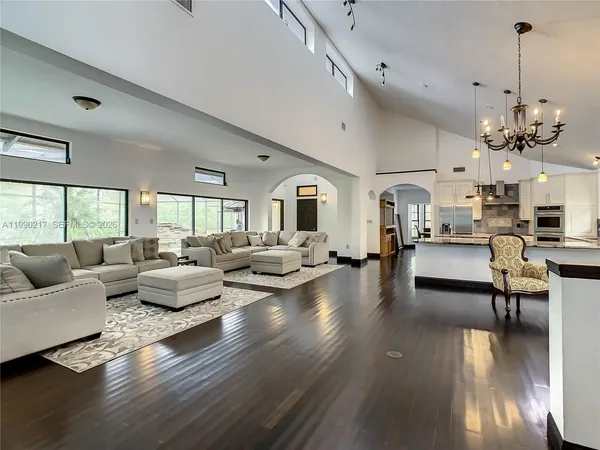 a view of a dining room and livingroom with furniture wooden floor a chandelier