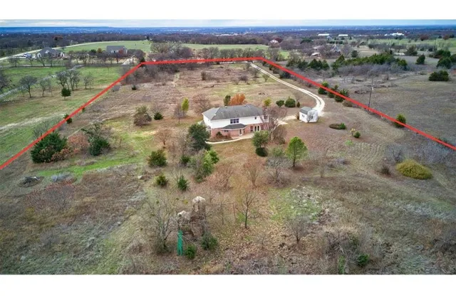 a view of a white house next to a yard with large trees