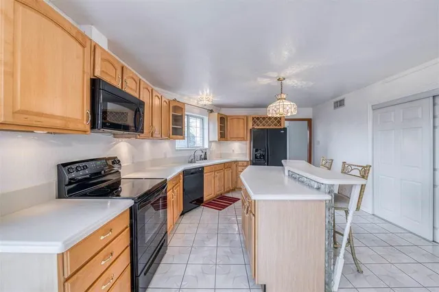 a kitchen with stainless steel appliances granite countertop a stove top oven a sink a dining table and chairs with wooden floor