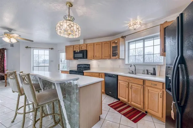 a kitchen with stainless steel appliances granite countertop a stove top oven a sink a dining table and chairs