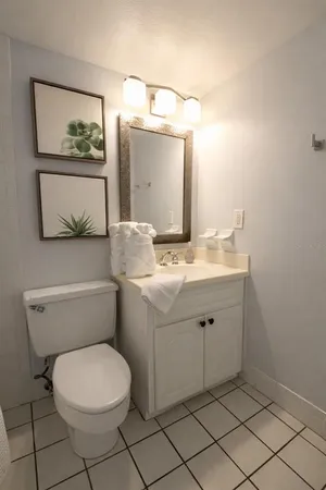 a white toilet sitting next to a white sink and vanity