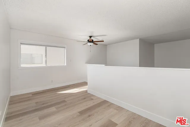 a view of a room with wooden floor and a ceiling fan