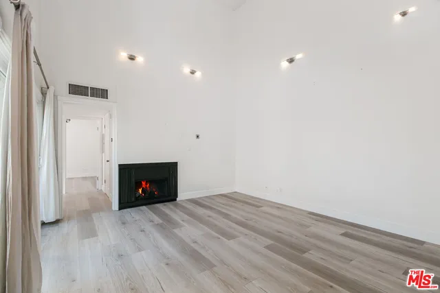 a view of an empty room with wooden floor and a fireplace