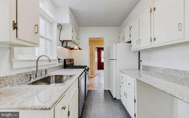 a kitchen with granite countertop a sink stainless steel appliances and white cabinets