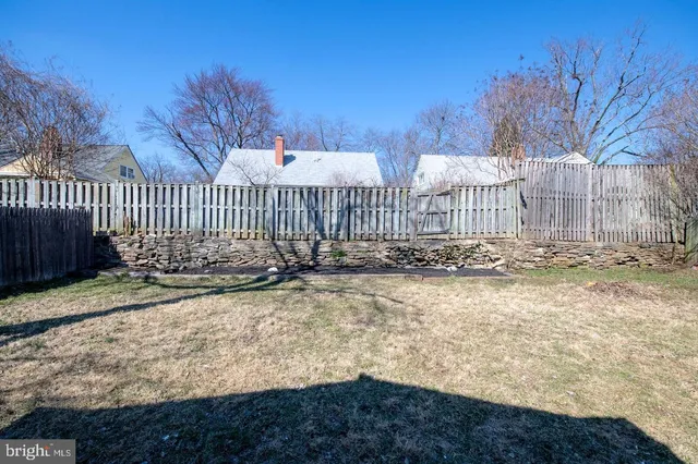 a view of a yard with wooden fence and trees