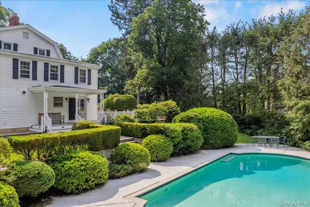 a view of a house with swimming pool lawn chairs and a yard