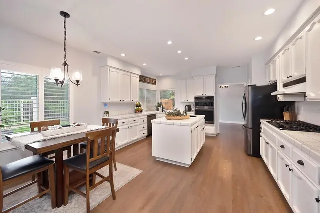 a kitchen with stainless steel appliances kitchen island granite countertop a sink a stove a refrigerator and island with wooden floor