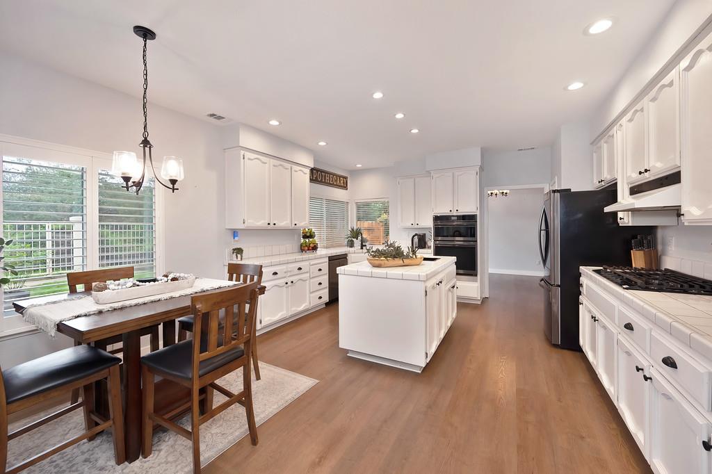 113 Ballast Way Folsom, CA 95630 - Photo 15 of 42 a kitchen with stainless steel appliances kitchen island granite countertop a sink a stove a refrigerator and island with wooden floor