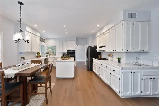 a kitchen with white cabinets and chairs
