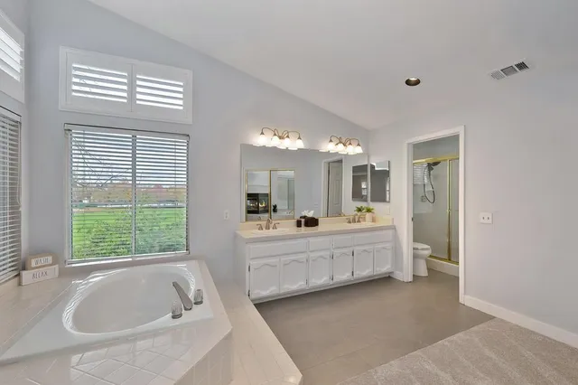 a large bathroom with a tub sink shower and mirror