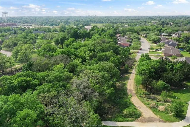 an aerial view of residential houses with outdoor space and trees