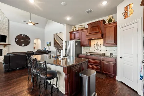 a kitchen with stainless steel appliances kitchen island granite countertop a table chairs in it and wooden floors