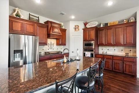 a kitchen with stainless steel appliances granite countertop a refrigerator and wooden cabinets