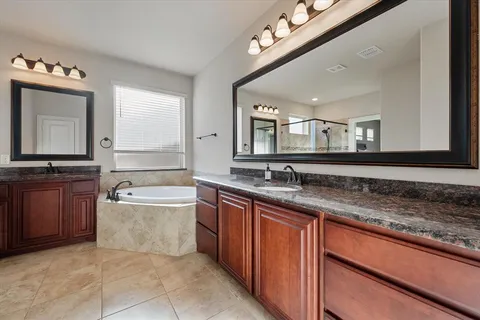 a bathroom with a granite countertop bathtub a sink and a large mirror