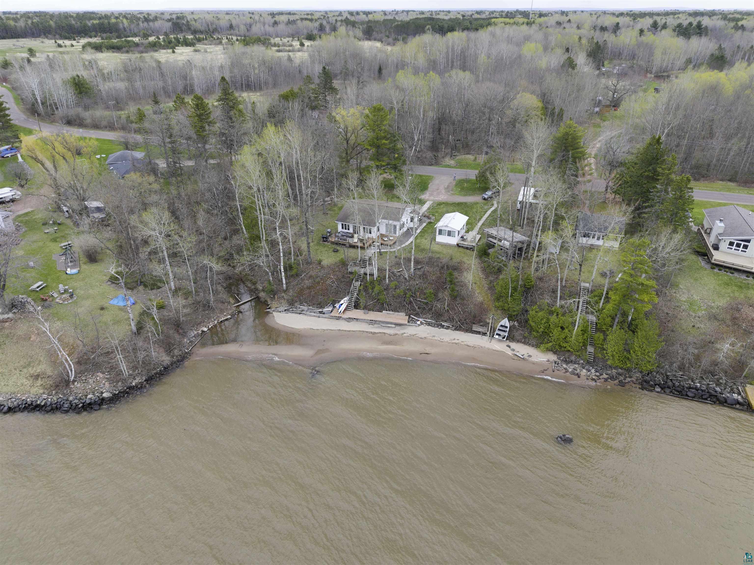 4107 B Lake Park Road Ashland, WI 54806 - Photo 21 of 23 Waterfront property featuring a sandy beach, mature trees, and a residential structure with a light-colored exterior