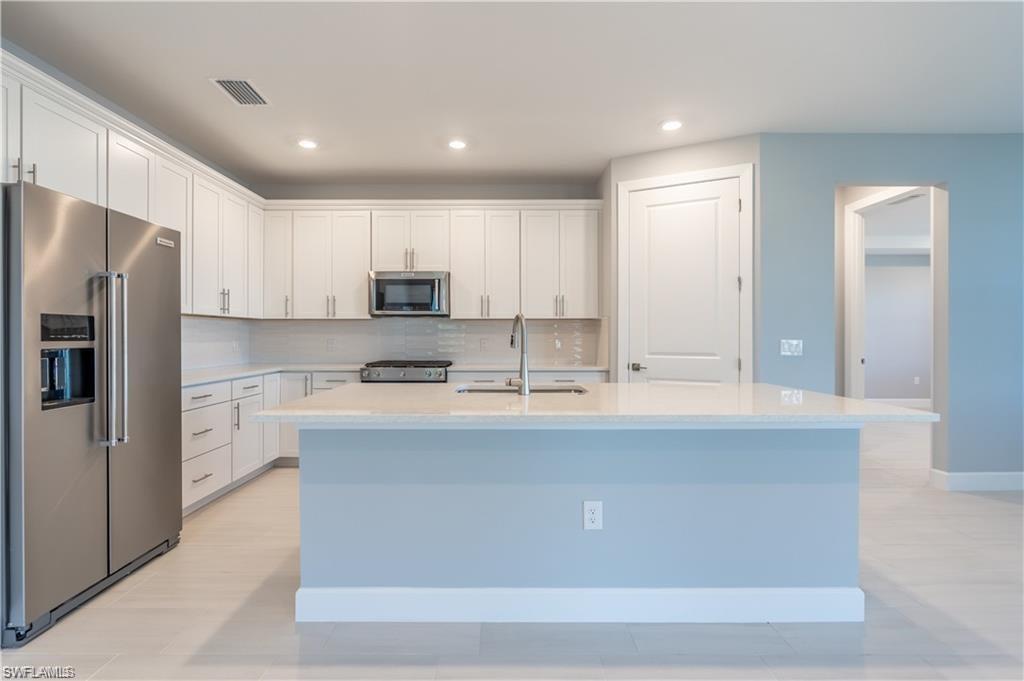 20207 Napa Loop Estero, FL 33928 - Photo 11 of 42 a large kitchen with stainless steel appliances granite countertop a sink a stove a refrigerator and white cabinets