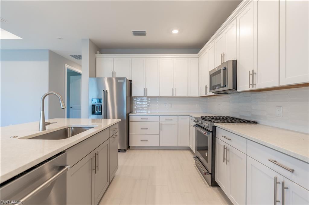 20207 Napa Loop Estero, FL 33928 - Photo 13 of 42 a kitchen with stainless steel appliances granite countertop a sink stove and refrigerator