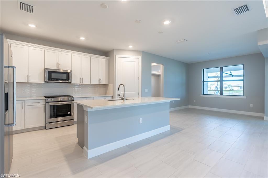 20207 Napa Loop Estero, FL 33928 - Photo 10 of 42 a kitchen with kitchen island a sink stainless steel appliances and cabinets