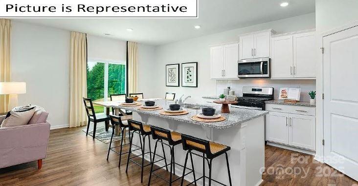 1365 Secrest Cmns Drive Monroe, NC 28112 - Photo 2 of 21 a kitchen with stainless steel appliances kitchen island granite countertop a stove a sink a dining table and chairs