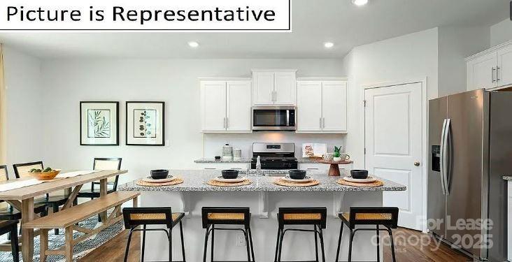 1365 Secrest Cmns Drive Monroe, NC 28112 - Photo 3 of 21 a kitchen with stainless steel appliances a table chairs and a refrigerator