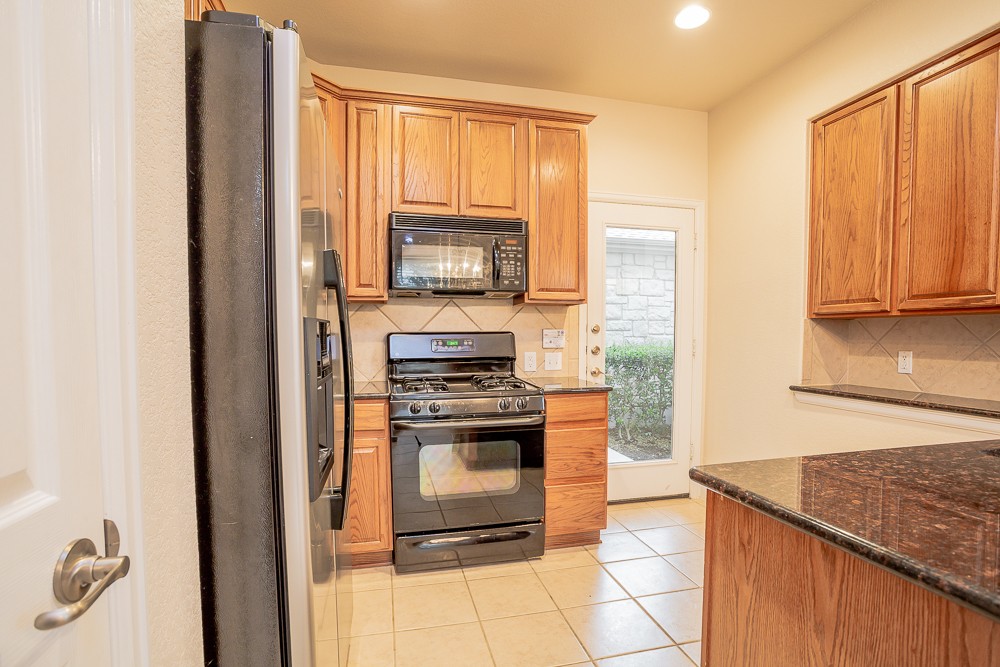 14812 Avery Ranch Boulevard, Unit 28 Austin, TX 78717 - Photo 9 of 21 a kitchen with stainless steel appliances granite countertop a stove a microwave and a refrigerator