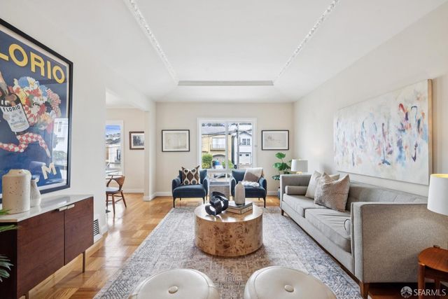 a living room with furniture and painting on the wall next to a window