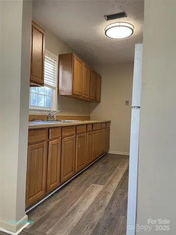a kitchen with stainless steel appliances granite countertop a sink and cabinets with wooden floor