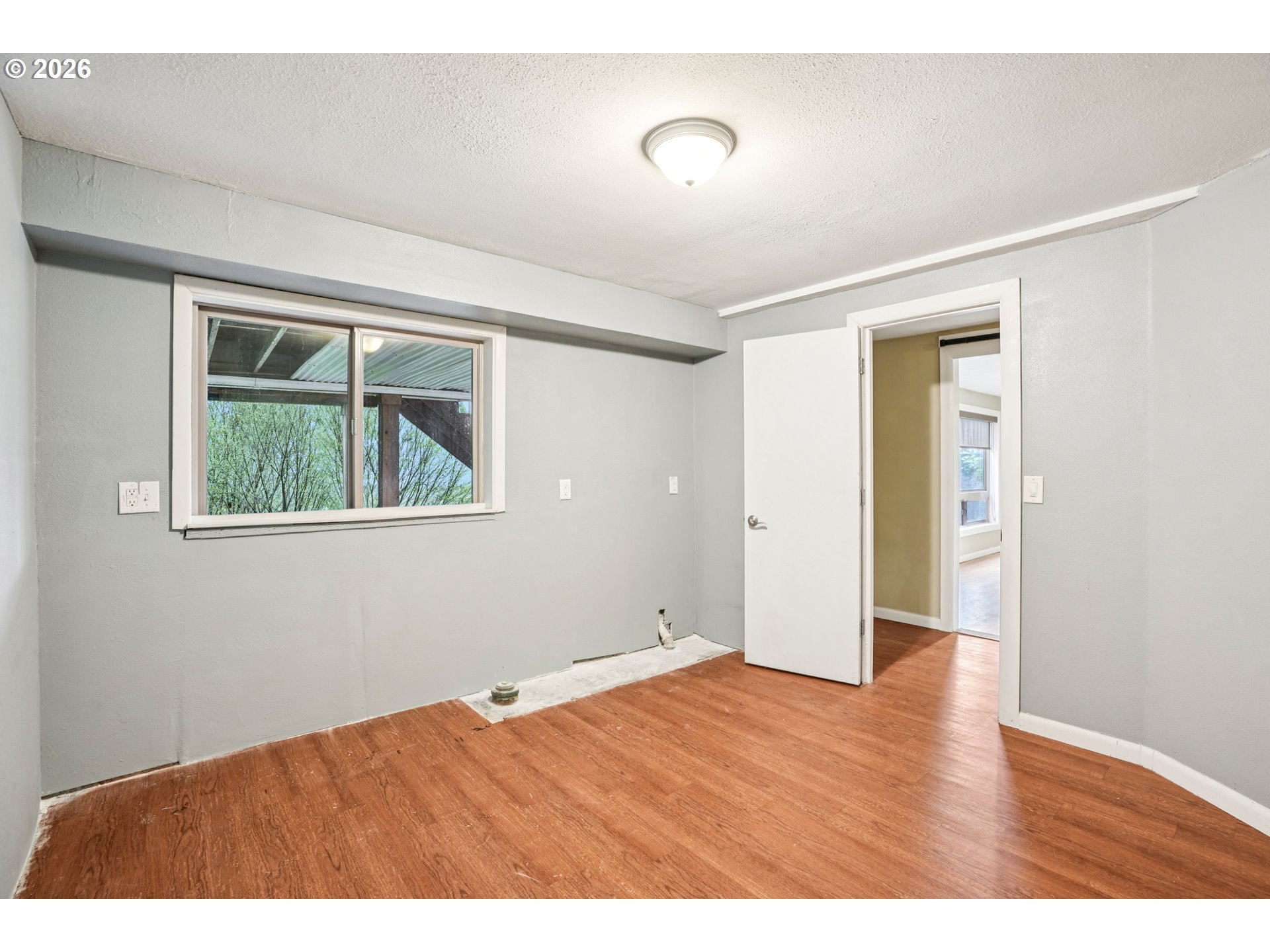 12444 Southwest 57th Avenue Portland, OR 97219 - Photo 27 of 44 a view of an empty room with wooden floor and a window