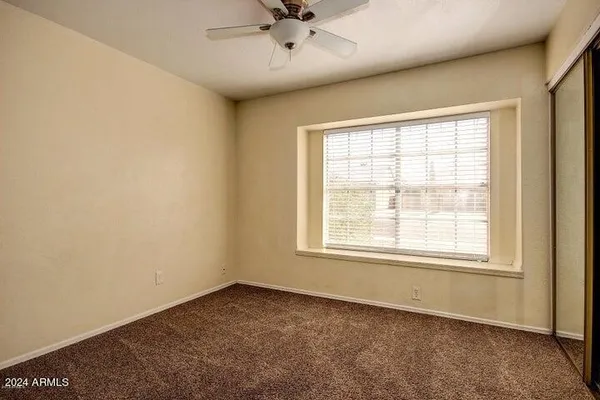 an empty room with a ceiling fan and window