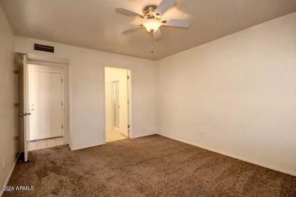 a view of a big room with carpet and a chandelier fan