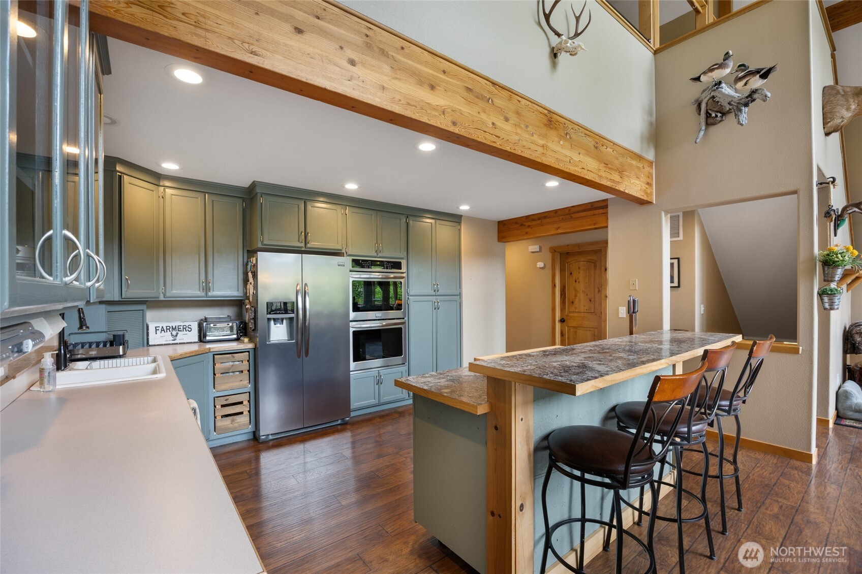 11125 Entiat River Road Entiat, WA 98822 - Photo 14 of 40 a kitchen with stainless steel appliances kitchen island granite countertop a refrigerator a stove and a sink with wooden floor