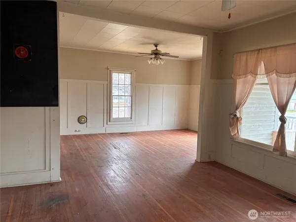 an empty room with wooden floor and windows