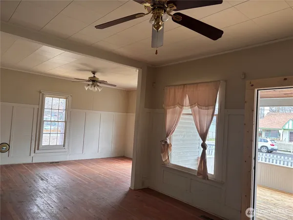 a view of empty room with wooden floor and fan