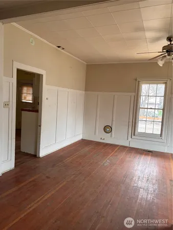 a view of an empty room with wooden floor and a window