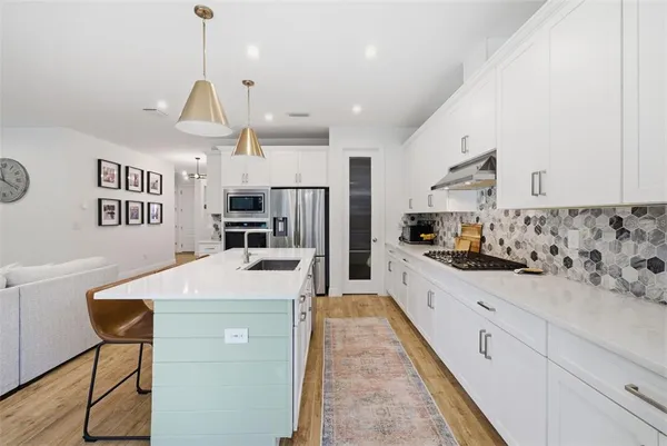 a kitchen with stainless steel appliances granite countertop a sink a stove a refrigerator and chairs