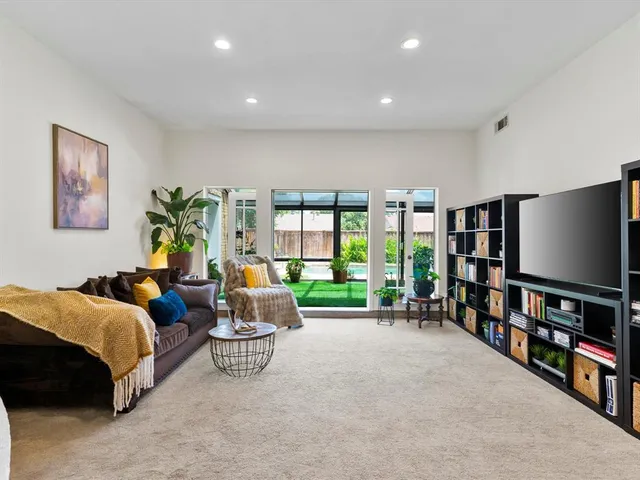 a living room with furniture a bookshelf and a flat screen tv