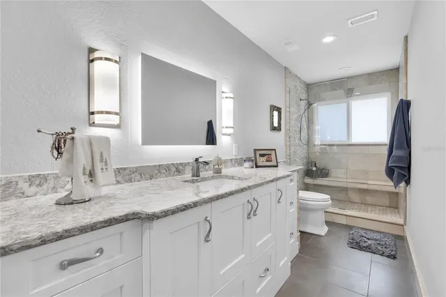 a bathroom with a granite countertop sink mirror and a toilet